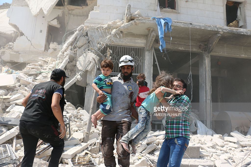 Syrian civilians and a rescue worker evacuate children in the Maadi district of eastern Aleppo after regime aircrafts reportedly dropped explosive-packed barrel bombs on August 27, 2016. At least 15 civilians were reported killed when two bombs fell several minutes apart, near a tent where people were receiving condolences for those killed this week. ALHALBI